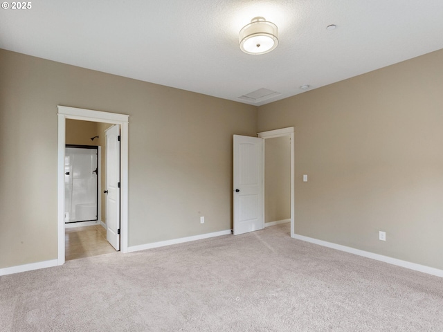 unfurnished bedroom featuring light carpet, baseboards, and ensuite bath