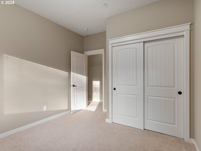 unfurnished bedroom featuring a closet, baseboards, and carpet flooring