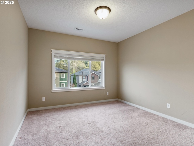 carpeted empty room with visible vents, a textured ceiling, and baseboards