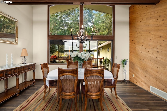 dining area with wooden walls, dark hardwood / wood-style flooring, and a notable chandelier