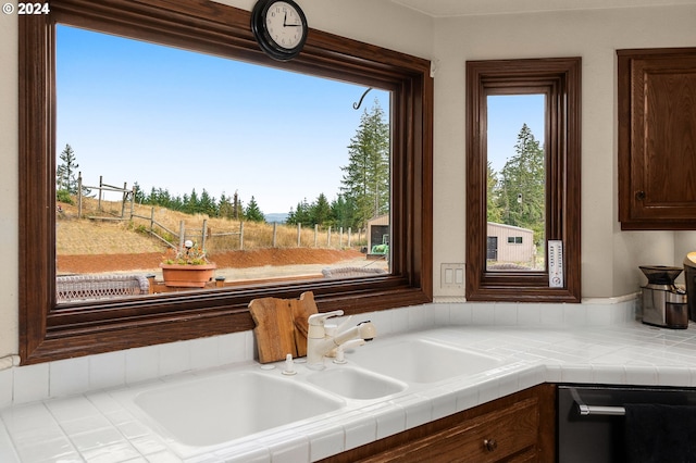 kitchen featuring dark brown cabinets, tile countertops, sink, and stainless steel dishwasher