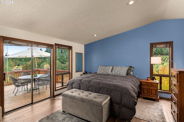 bedroom featuring multiple windows, lofted ceiling, light hardwood / wood-style flooring, and access to exterior