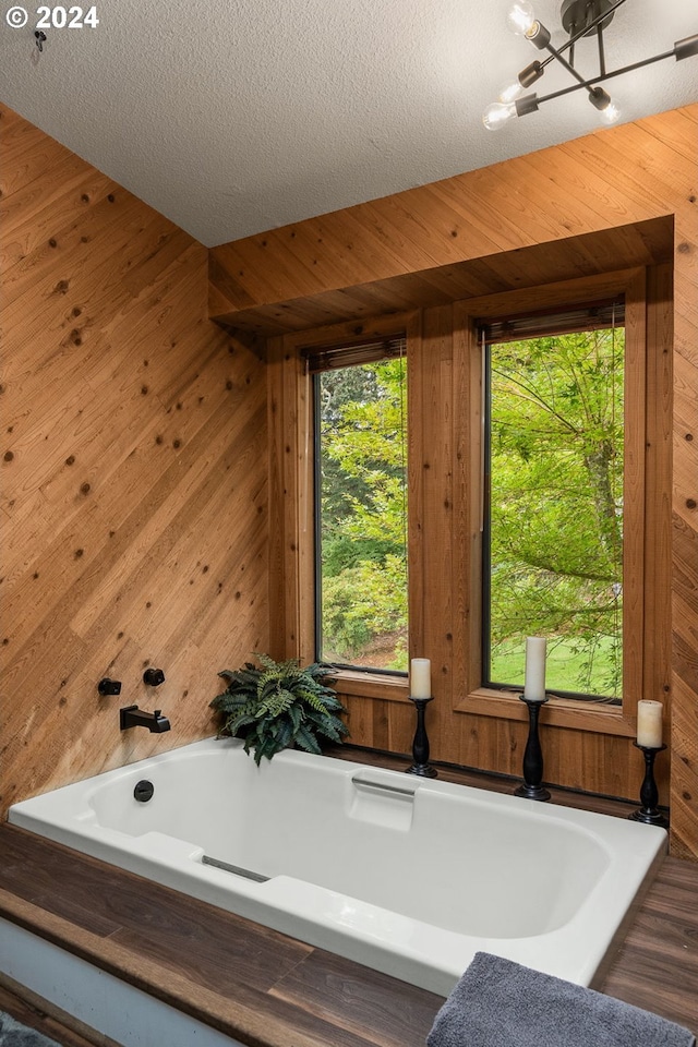 bathroom featuring wood-type flooring, wood walls, a textured ceiling, and a washtub