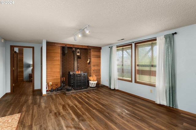 unfurnished living room with a textured ceiling, dark wood-type flooring, and a wood stove