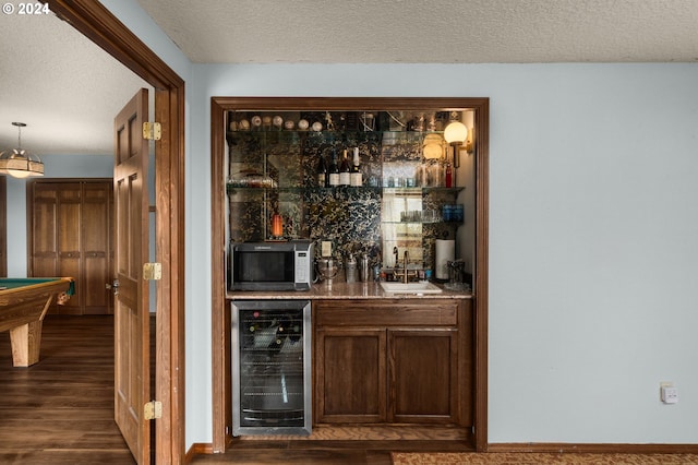 bar featuring sink, beverage cooler, a textured ceiling, dark hardwood / wood-style floors, and pool table