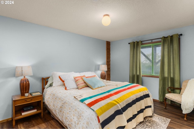 bedroom with a textured ceiling and dark wood-type flooring