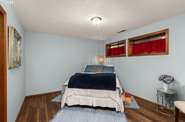 bedroom with a textured ceiling and dark wood-type flooring