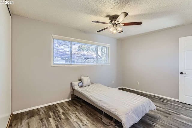 bedroom with ceiling fan, a textured ceiling, and dark hardwood / wood-style flooring