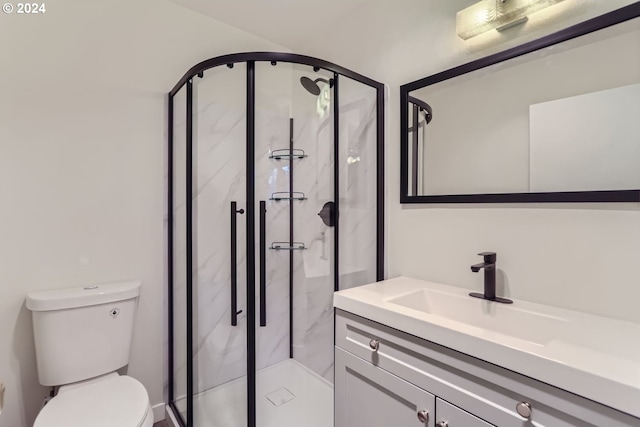 bathroom featuring vanity, a shower with shower door, and toilet