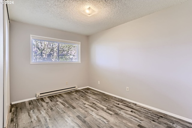 empty room featuring hardwood / wood-style flooring, a baseboard radiator, and a textured ceiling