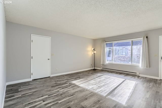 spare room featuring a baseboard heating unit, wood-type flooring, and a textured ceiling