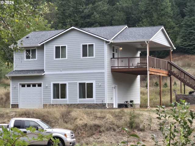 back of house featuring a garage and a wooden deck