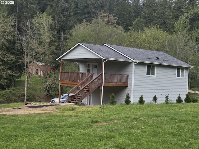 rear view of property with a wooded view, a lawn, a porch, roof with shingles, and stairs