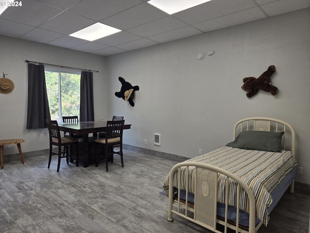 bedroom featuring a drop ceiling and hardwood / wood-style floors