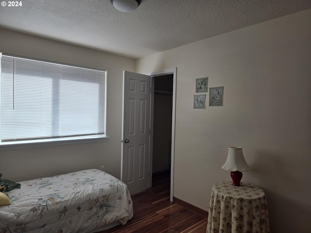 bedroom with a textured ceiling, baseboards, and dark wood-style flooring