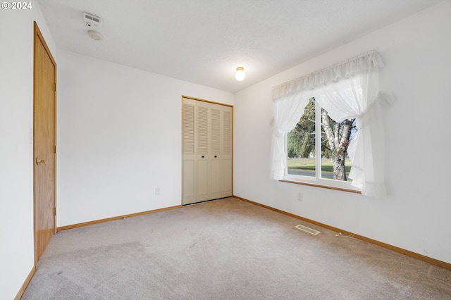 unfurnished bedroom featuring a closet, carpet floors, and a textured ceiling