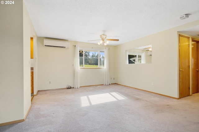 carpeted spare room with an AC wall unit, a textured ceiling, and ceiling fan