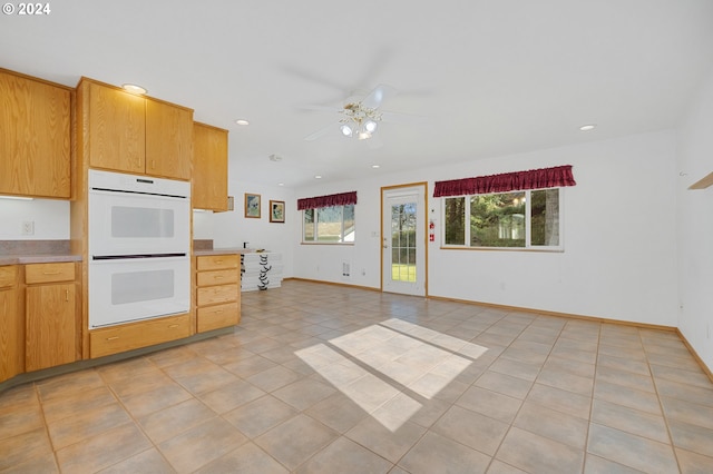 kitchen featuring ceiling fan, light tile patterned floors, and white double oven