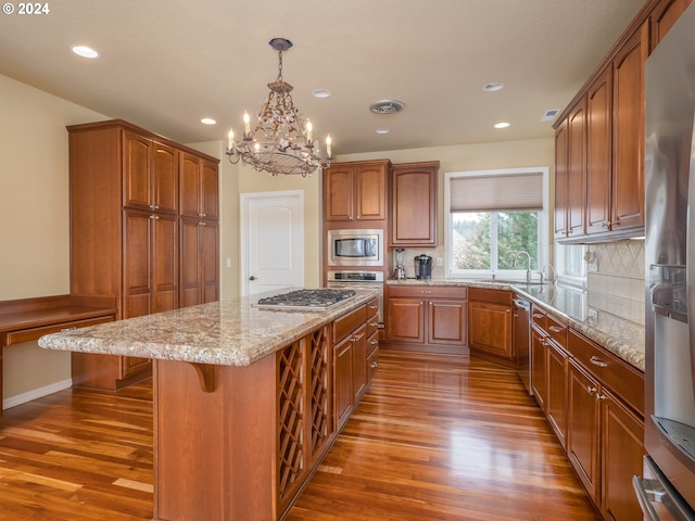 kitchen with a center island, stainless steel appliances, dark wood-type flooring, pendant lighting, and a chandelier