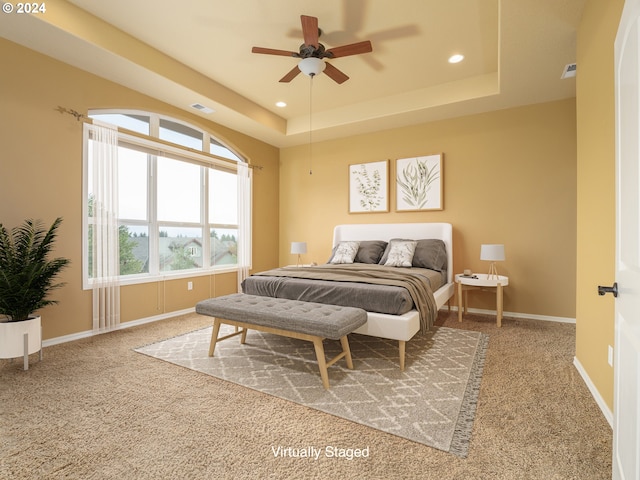 carpeted bedroom featuring ceiling fan and a raised ceiling