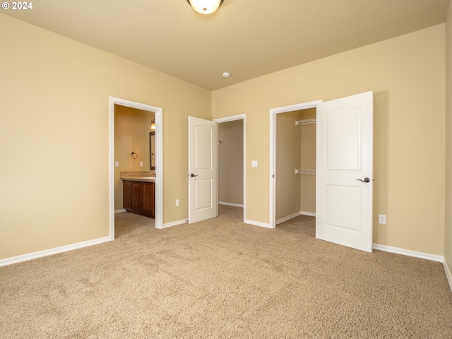 unfurnished bedroom featuring ensuite bathroom and light carpet