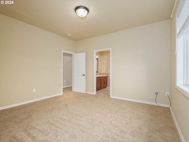 unfurnished bedroom with light colored carpet and ensuite bath