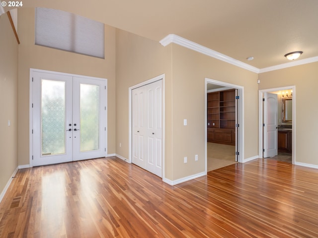 entrance foyer with french doors, crown molding, and hardwood / wood-style floors