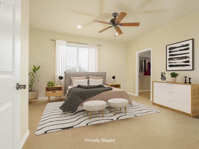 bedroom featuring ceiling fan, light colored carpet, a closet, and a walk in closet