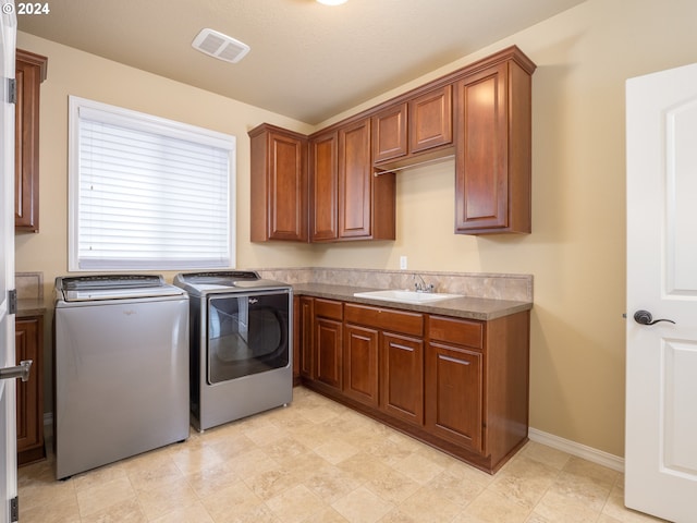 laundry area featuring cabinets, a textured ceiling, sink, and washing machine and dryer