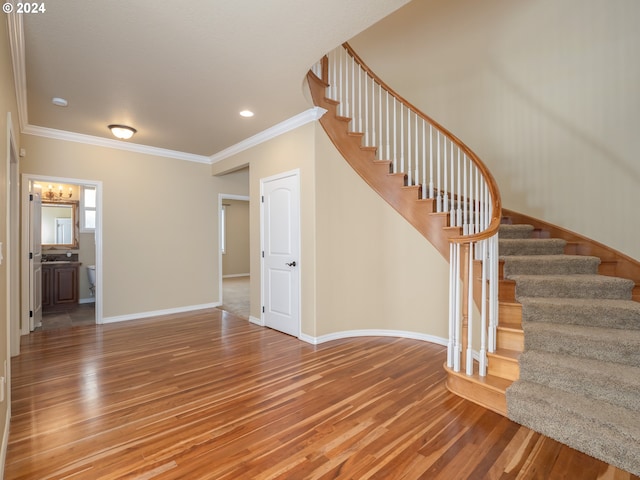 stairs with ornamental molding, a chandelier, and hardwood / wood-style floors