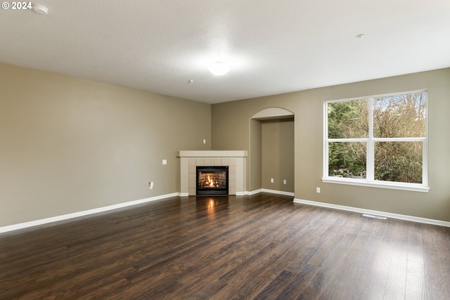 unfurnished living room featuring a tile fireplace and dark hardwood / wood-style flooring