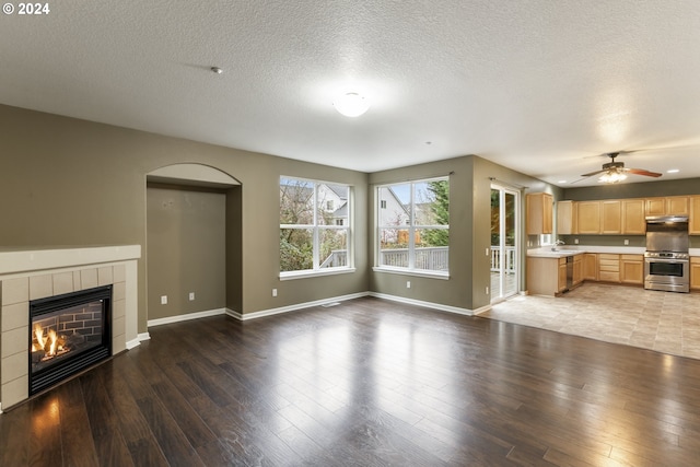 unfurnished living room featuring hardwood / wood-style floors, ceiling fan, sink, and a tile fireplace