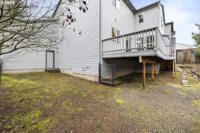 rear view of property featuring a deck and a lawn