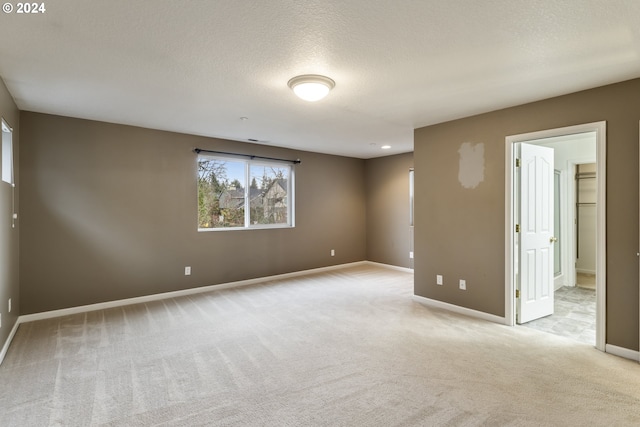 carpeted empty room featuring a textured ceiling