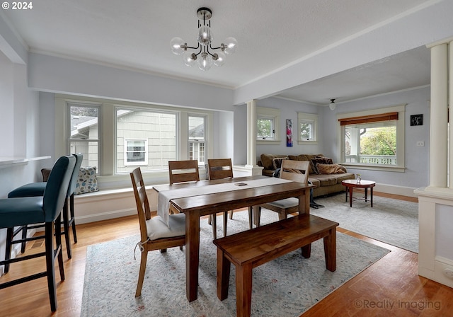 dining space with ornate columns, light hardwood / wood-style floors, an inviting chandelier, and ornamental molding