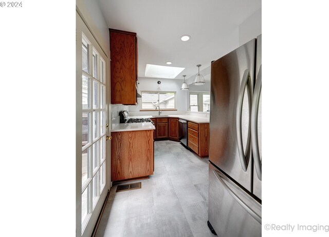 kitchen with a skylight, hanging light fixtures, sink, kitchen peninsula, and appliances with stainless steel finishes