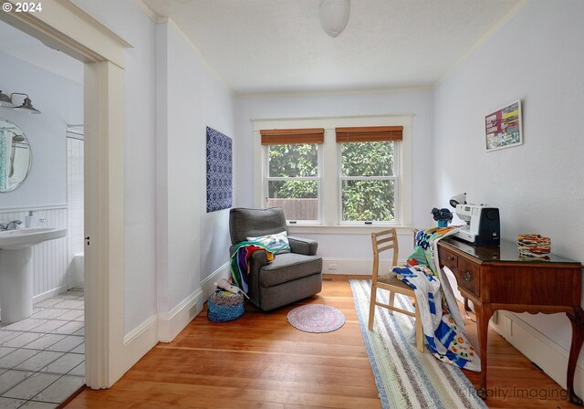 sitting room with crown molding and light wood-type flooring