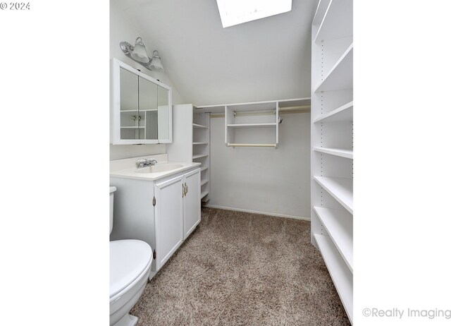 bathroom with lofted ceiling with skylight, toilet, and vanity