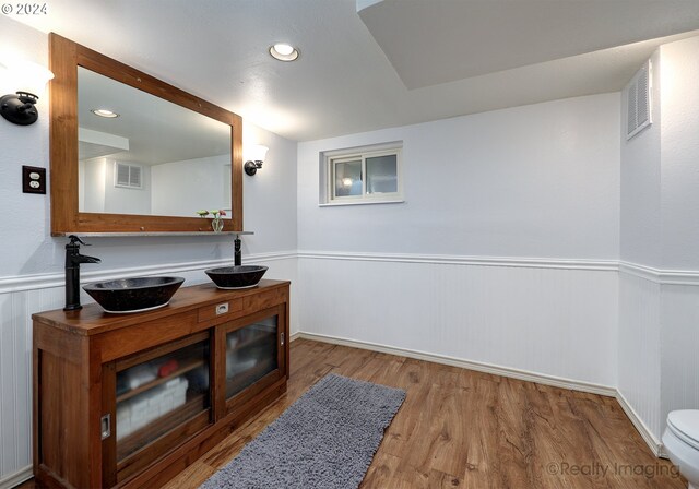 interior space featuring wood-type flooring, vanity, and toilet