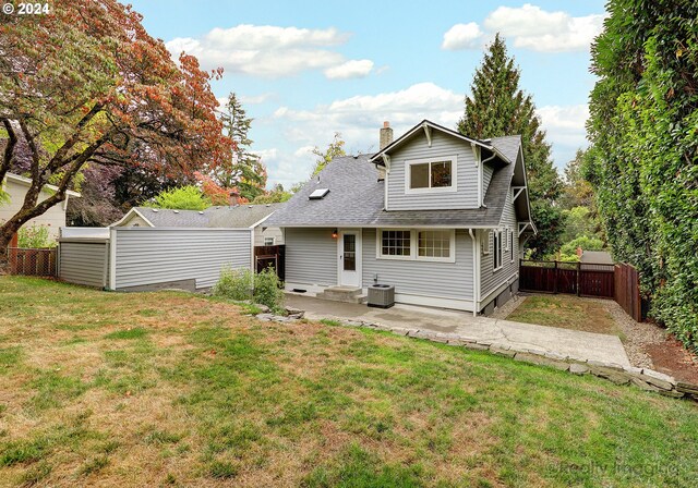 rear view of house featuring central air condition unit, a patio, a yard, and a storage unit