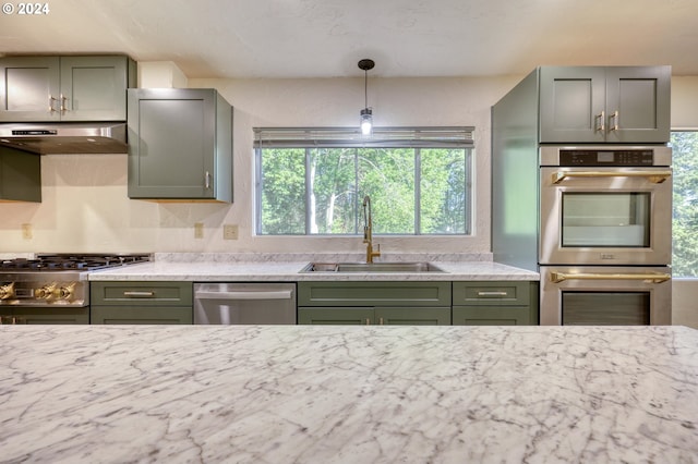 kitchen featuring sink, stainless steel appliances, decorative light fixtures, extractor fan, and light stone countertops