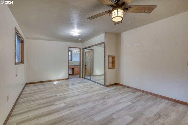 empty room with a textured ceiling, ceiling fan, and light hardwood / wood-style flooring