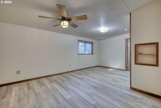 unfurnished room with ceiling fan, a textured ceiling, and light wood-type flooring