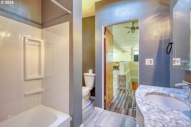full bath with vanity, wood finish floors, toilet, a textured wall, and ceiling fan