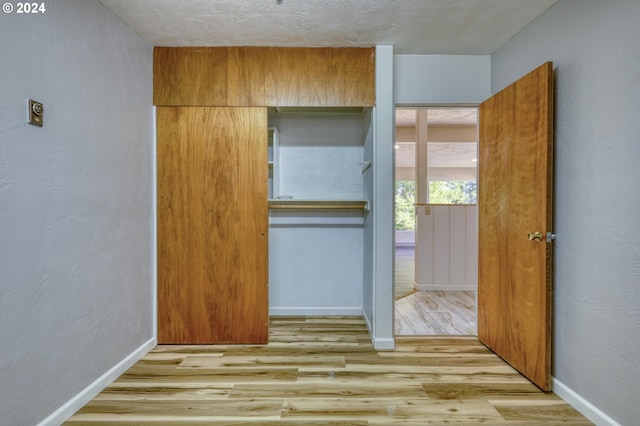 unfurnished bedroom featuring light wood-type flooring, a textured ceiling, and a closet