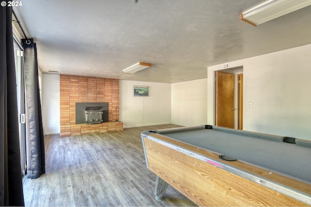 playroom with a brick fireplace, wood-type flooring, pool table, and a wood stove