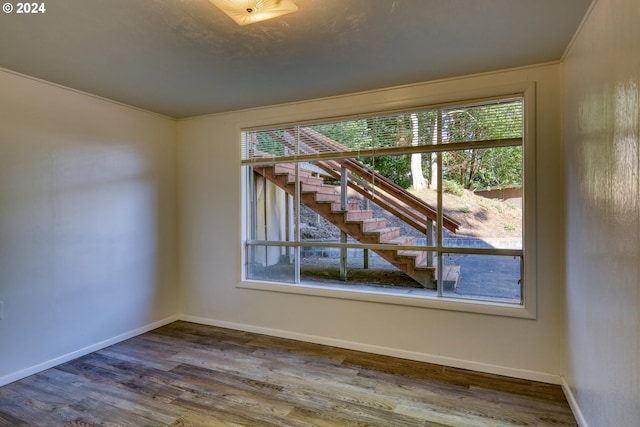 empty room featuring baseboards, stairs, and wood finished floors