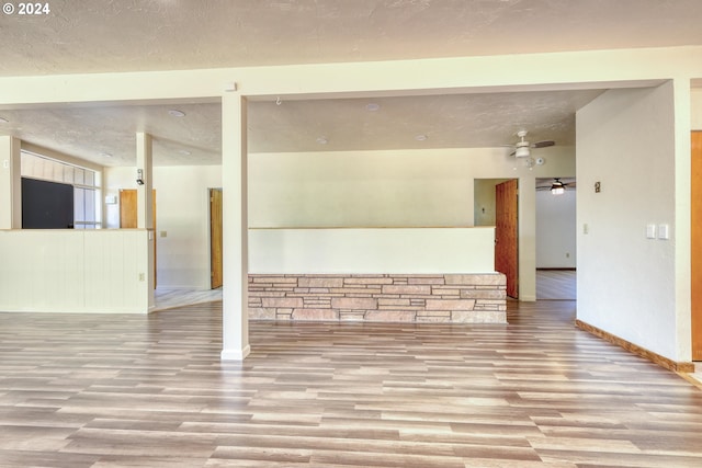 unfurnished living room with ceiling fan, a textured ceiling, and light hardwood / wood-style floors