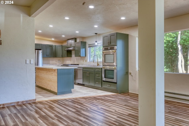 kitchen featuring light wood-type flooring, light countertops, a textured wall, and stainless steel appliances
