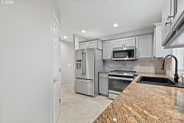 kitchen with light stone counters, stainless steel appliances, light tile patterned floors, tasteful backsplash, and sink